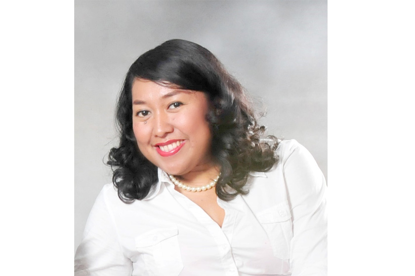 A woman with curly long hair wearing pearl necklace and white blouse